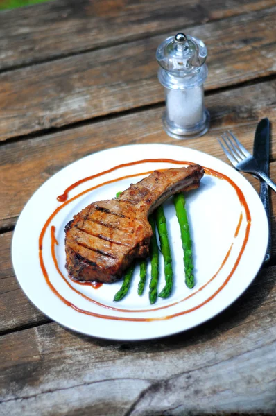 Grilled porkchop on the bone served with asparagus — Stock Photo, Image