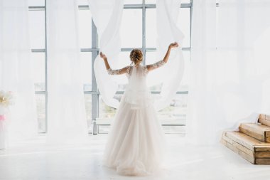 a beautiful bride in a magnificent dress throws the curtains