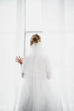 a beautiful bride in a magnificent dress throws the curtains