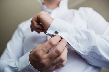 Düğün, damat giyinir, koluna bir düğme takar.