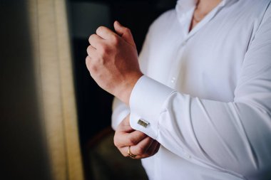 Düğün, damat giyinir, koluna bir düğme takar.