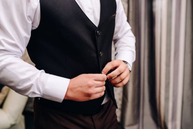 Düğün, damat giyinir, koluna bir düğme takar.