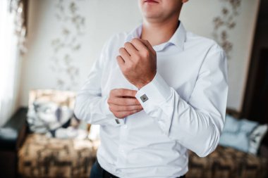 Düğün, damat giyinir, koluna bir düğme takar.