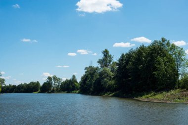 Yaz, günbatımından önce göl, ormanlık kıyılar.