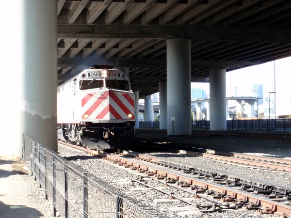 Train moves along tracks under highway — Stock Photo, Image