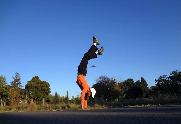 Man Handstands with plane flying in the sky above — Zdjęcie stockowe
