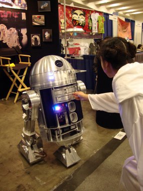 Woman Dressed as Princess Leia reaches out to touch R2-D2 replic clipart