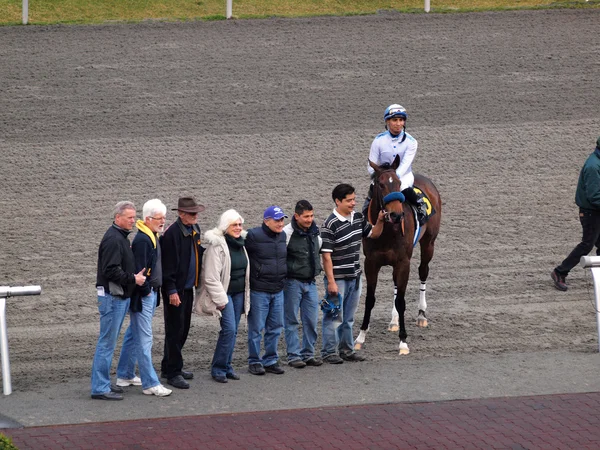 Jockey y los propietarios de caballos posan con el caballo después de ganar la carrera — Foto de Stock