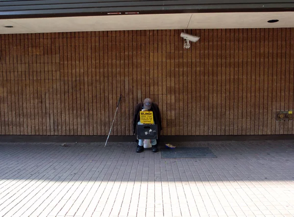 El hombre ciego se sienta agianst lado de la construcción como él pide "Ayuda en — Foto de Stock