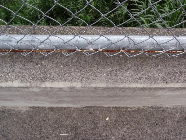 Rusted Chain link fence and concrete sidewalk its attached to — Stock Photo, Image