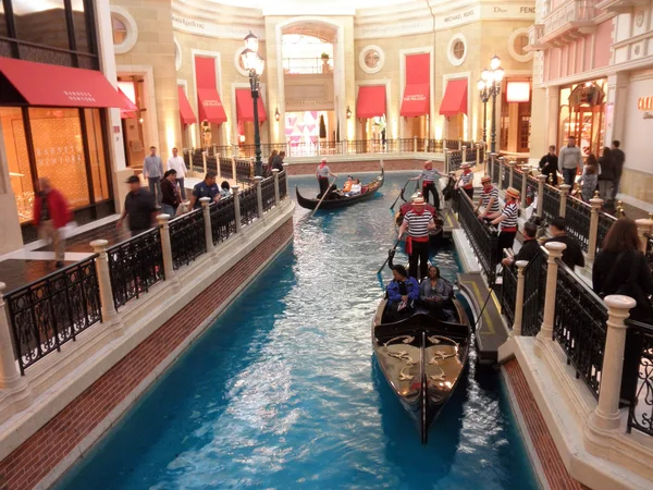 Les gens montent gondoles dans la rive entourée de magasins à l'intérieur de la — Photo