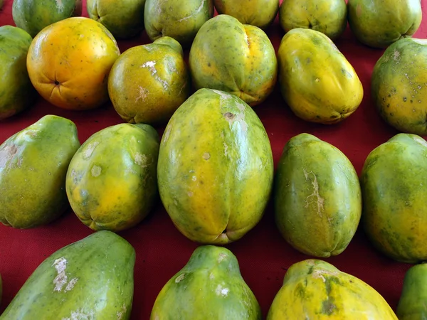 Filas de papayas hawaianas sobre tela roja — Foto de Stock