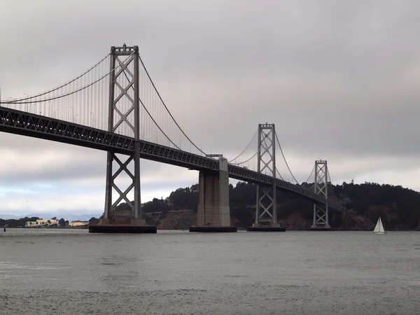 Boat sail by the San Francisco side of Bay Bridge on a foggy day — Stock Photo, Image