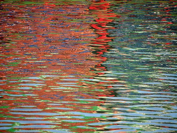 Rojo Azul El patrón de color brilla y se refleja en las ondas de agua — Foto de Stock