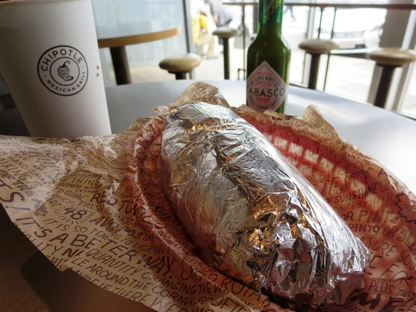 在 Chipotle 用饮料和绿色塔巴斯科包裹的 burrito — 图库照片