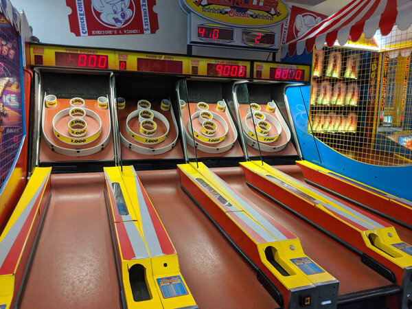 Honolulu - September 15, 2019:  Four Skee-Ball tables for play in arcade at Chuck E. Cheese.   It is played by rolling a ball up an inclined lane and over a "ball-hop" hump that jumps the ball into bullseye rings. The object of the game is to collect