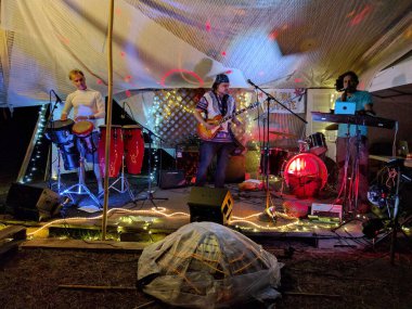 Oahu - 18 Şubat 2017: Jerome James ve Tommy Osuna Oahu 'nun kuzey kıyısındaki Mokuleia Kampı' ndaki dev bir yelkenli altında Optimysstique 2017 Kampı 'nda gitar, davul ve bilgisayar çalıyorlar..