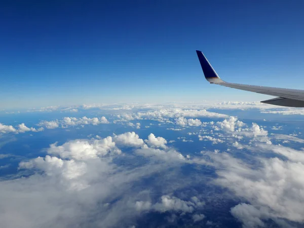 天空中的高空 用一架商业喷气式飞机的机翼 从云端上方射出 飞机左舷向上 下方是太平洋 — 图库照片