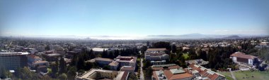 Birds eye view of UC Berkeley Campus with a mix of Historic and modern Buildings surrounded by trees with roads and paths intertwined with the landscape of the City of Berkeley in California looking towards San Francisco Bay.  Panoramic September 201