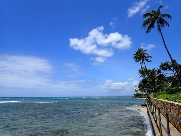 Elevated Shoreline Path to Makalei Beach with waves lapping, napakaa, lava rock wall and Coconut trees along the shore on a wonderful day in Oahu, Hawaii.  August 14, 2018.