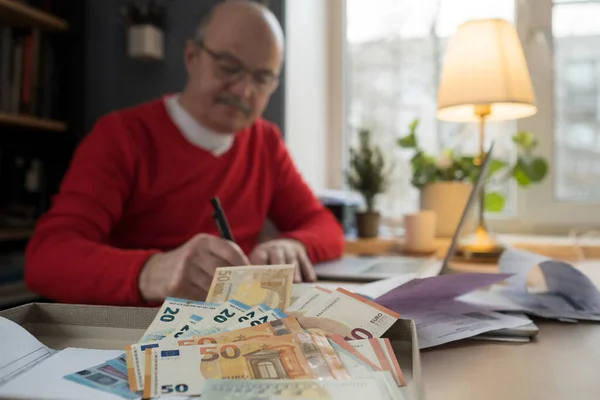 Hombre mayor con anteojos que cuenta el dinero de la jubilación y controla las finanzas — Foto de Stock