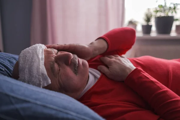 A sick male sleeping with wet towel on his forehead to reduce high high fever — Stock Photo, Image