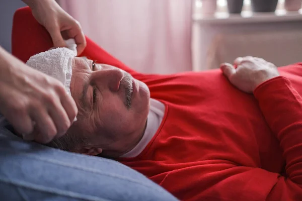 Больной мужчина спит с мокрым полотенцем на лбу, чтобы уменьшить высокую температуру — стоковое фото