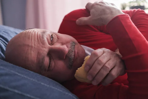 Senior caucasian man eating cake hiding from everyone — Fotografia de Stock