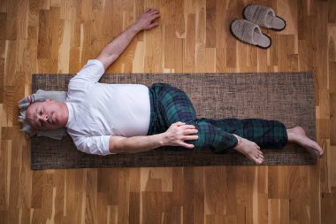 Üst düzey beyaz adam yoga yapıyor. Omurga bükme pozisyonu.