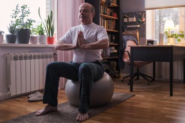 Son sınıf öğrencisi evde kaslarını esneten fitness topuyla egzersiz yapıyor..