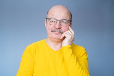 Gözlüklü yaşlı kel adam bir karar vermeye çalışıyor..