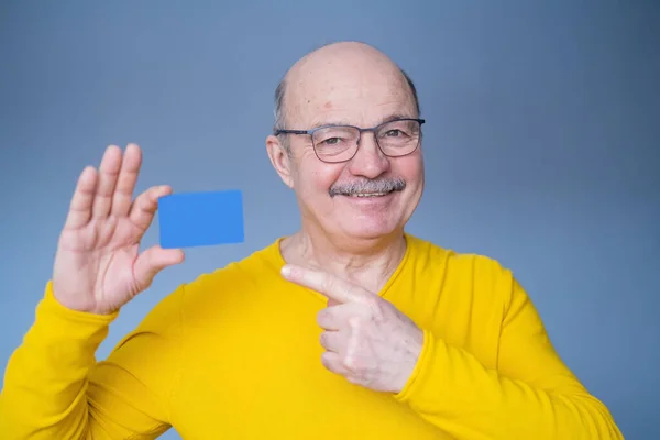 Senior mit Schnurrbart zeigt leere Visitenkarte oder Kreditkarte. — Stockfoto
