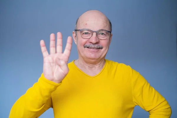 Senior man upp handen, visar nummer fyra med fingrar, räkna något — Stockfoto