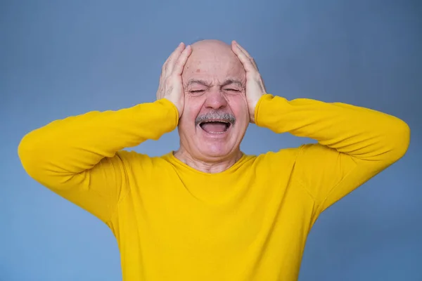 Älterer Mann, der seine Ohren mit erhobenen Handflächen bedeckt, hat schreckliche Kopfschmerzen. — Stockfoto