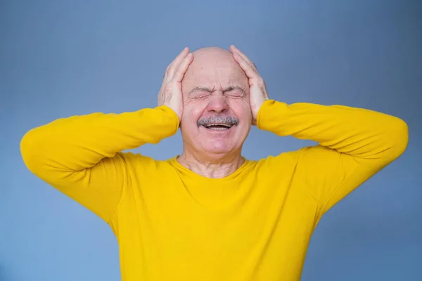 Älterer Mann, der seine Ohren mit erhobenen Handflächen bedeckt, hat schreckliche Kopfschmerzen. — Stockfoto