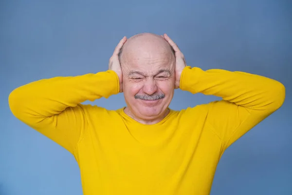 Älterer Mann, der seine Ohren mit erhobenen Handflächen bedeckt, hat schreckliche Kopfschmerzen. — Stockfoto