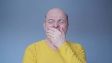 Yorgun, uykulu, yaşlı adam esniyor..