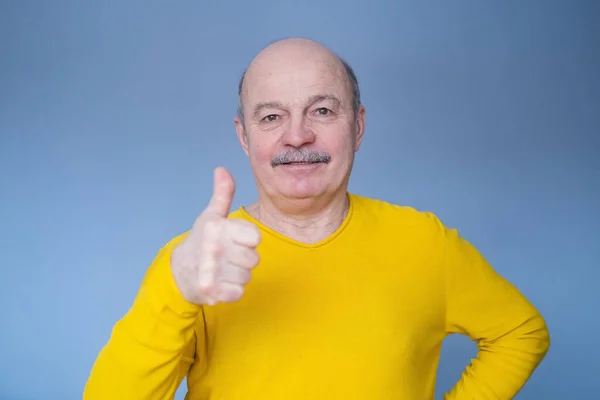 Stilig äldre man i gul tröja visar tummen upp. — Stockfoto