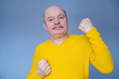 Orta yaşlı adam kollarını kaldırıp zaferi ya da başarıyı kutluyor..