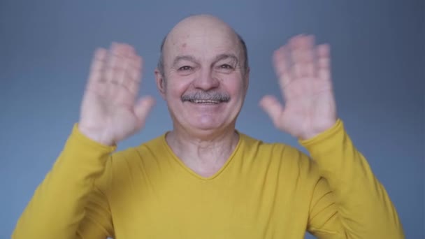 Старший лысый мужчина машет рукой приветствуя друзей. — стоковое видео