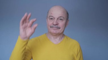 Son sınıftaki üzgün beyaz adam elleriyle hareket ediyor. Parmaklarıyla küçük boy işareti yapıyor.
