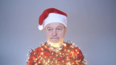 Kırmızı Noel şapkalı son sınıf üzgün adam çelenge sarılmış..