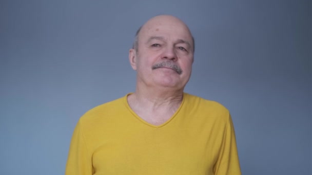Unavený starší muž má bolesti v krku nebo krku. Chlápek v neformálním žlutém tričku si dává pauzu. — Stock video
