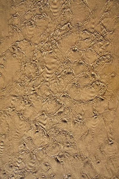 Agua que fluye sobre una playa de arena — Foto de Stock