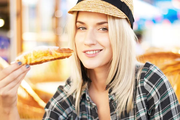 Young woman eats croissant — Stock Photo, Image