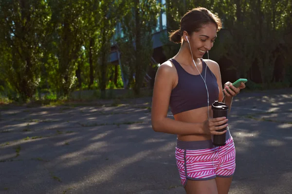 Happy fit girl using phone outdoors — Stock Photo, Image