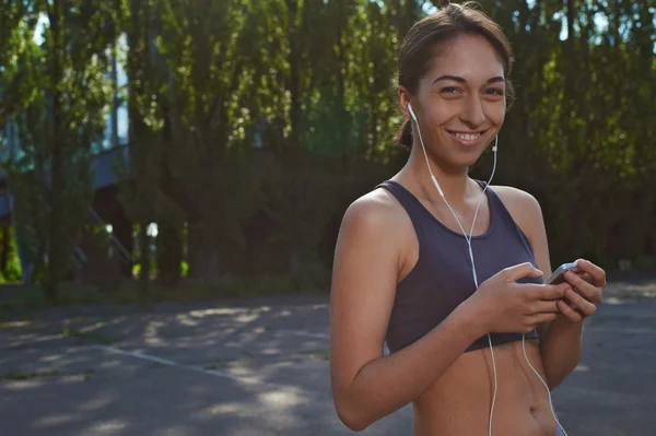 Happy fit girl using phone outdoors — Stock Photo, Image
