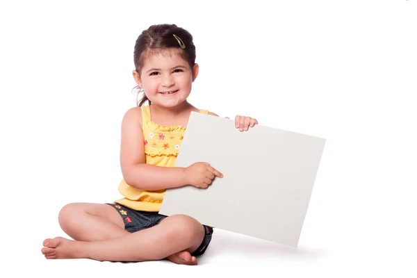 Menina feliz sentado apontando para quadro branco — Fotografia de Stock