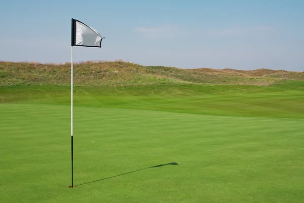 Bola de golfe em um campo verde e buraco — Fotografia de Stock