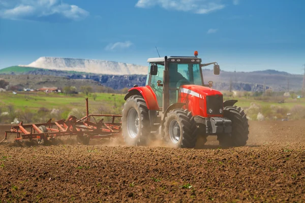 Trator vermelho novíssimo arar a terra — Fotografia de Stock